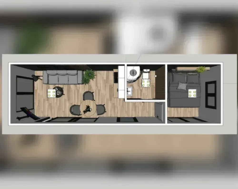 This is an architectural floor plan viewed from above, showing a long, narrow rectangular structure divided into two main zones. The larger left section serves as an open-plan living and kitchen area, featuring a grey sofa, round dining table with four chairs, a compact kitchenette, and a small bathroom with toilet and sink tucked into the middle. Wood-look flooring runs throughout this space, with a decorative plant accent near the seating area. A dividing wall separates this from the right-hand bedroom, which contains a large bed with grey linens, a nightstand, and what appears to be a wardrobe or closet unit against the far wall, also finished in matching wood flooring.