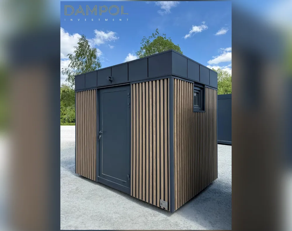 This compact modular structure has a clean, rectangular shape with a flat, slightly overhanging dark charcoal roof that caps the design neatly. The exterior combines two materials: smooth dark grey-anthracite panels along the corners and upper band, paired with vertical wood-toned slatted cladding across the main wall surfaces, creating a striking contrast of textures. A single solid door, painted in matching dark grey, sits centrally on the front-facing wall, framed by the slatted paneling on either side. To the right of the door, a small square window with a dark frame is set into the side wall, offering the only visible glazing. The overall proportions are boxy and modern, with crisp edges and a minimalist, cabin-like aesthetic.