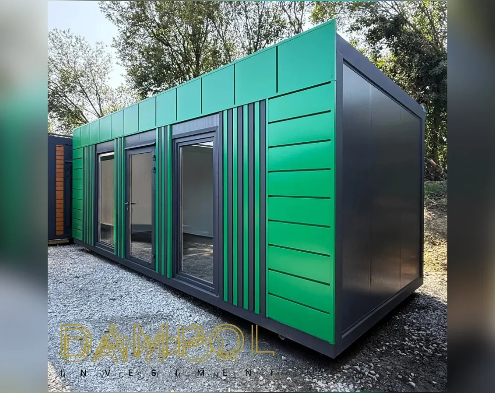 This modular garden building is a rectangular, single-story structure with a sleek mono-pitch roof that slopes gently from a taller front edge down to the back. The front and side façades are clad in vibrant emerald-green paneling, horizontally ribboned on the sides and vertically striped near the entrance, all trimmed in dark charcoal-grey framing. The front wall features three full-height glass elements: a wide fixed window on the left, a central double-leaf glass door, and another large window on the right, all framed in matching dark grey. The long side panel is solid dark grey/black, unbroken by openings, giving a striking two-tone contrast against the green.